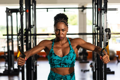 Muscular woman doing arm exercises on a machine at the gym. determination and focus.