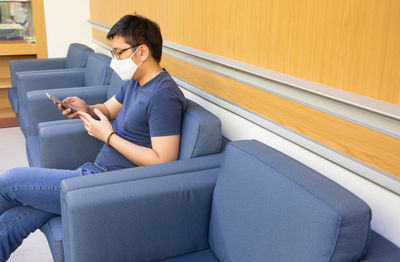 Young woman using mobile phone while sitting on sofa