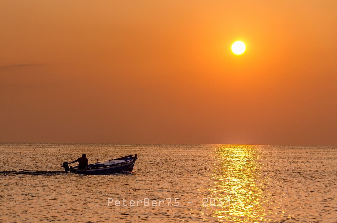 SILHOUETTE MAN IN SEA AGAINST ORANGE SUNSET SKY