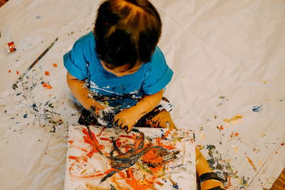 High angle view of messy baby boy with canvas sitting at home