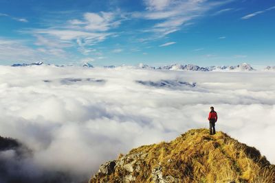 Rear view of man standing on mountain against sky