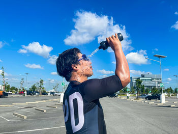 Side view portrait of man in city against sky