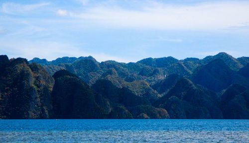 Scenic view of sea and mountains against sky