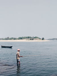 Man fishing in sea against clear sky