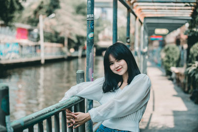 Portrait of woman standing against railing