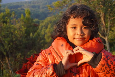 Expression of a cheerful girl with both hands making a love peace sign symbol on summer vacation