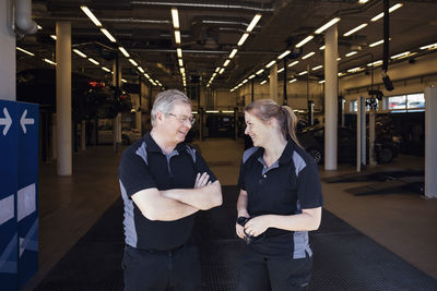 Happy experts discussing while standing at auto repair shop