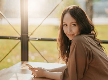 Portrait of smiling woman using mobile phone in cafe