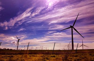 Windmill on field against cloudy sky