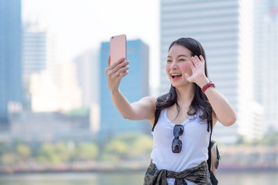 Happy young woman using mobile phone in city