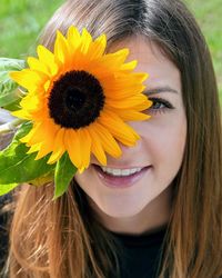 Close-up portrait of smiling woman with sunflower