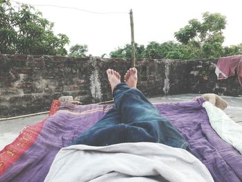 Low section of man relaxing against trees