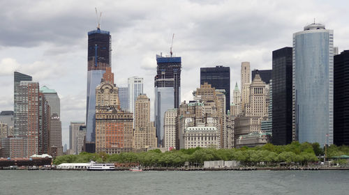 Modern buildings by river against sky in city