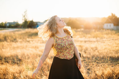 Young woman with tousled hair standing on field