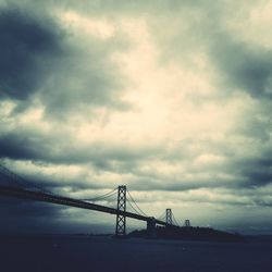 Bridge over river against cloudy sky