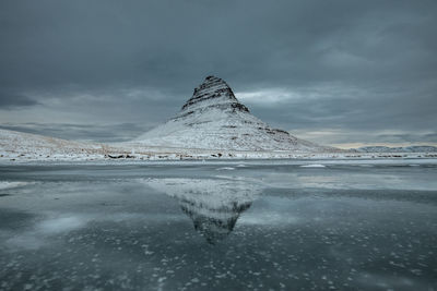 Scenic view of frozen lake by snowcapped mountain against sky