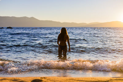 Mountain lake teen swims at sunset or sunrise for travel and adventure