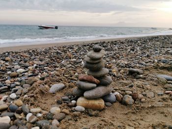 Pebbles on shore at beach against sky