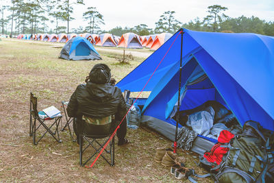 Rear view of men sitting on chair on field