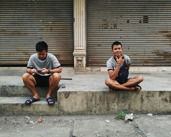 Full length of young man sitting on wall