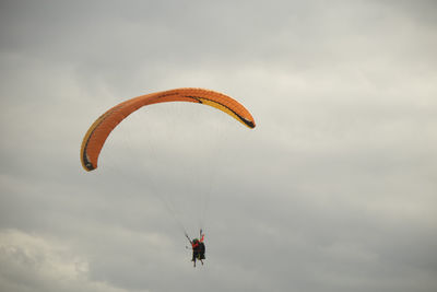 Low angle view of person paragliding against sky