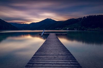 Pier over lake against sky during sunset