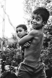 Portrait of happy siblings standing against trees