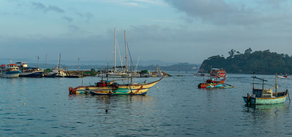 Sailboats moored in sea against sky