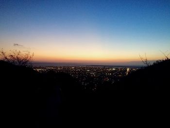 Silhouette cityscape against clear sky during sunset