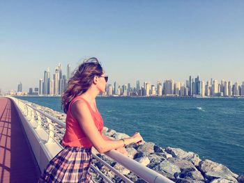 Woman standing on promenade while looking at skyline