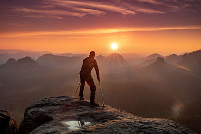 Man standing on mountain against sky during sunset