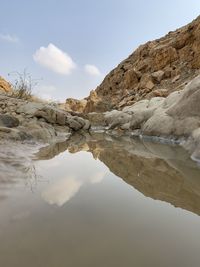 Reflection of rocks in water against sky