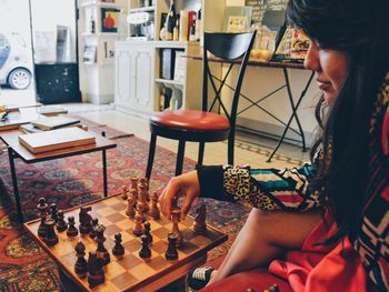 Woman playing chess at table in home