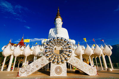 Low angle view of buddha statues against blue sky