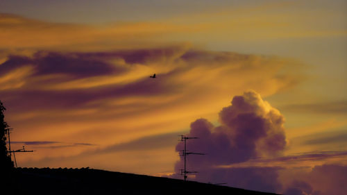 Golden dramatic cloudy sky at sunset golden hour in bangkok thailand with roof antennae silhouette