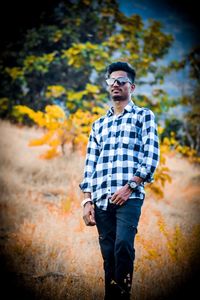 Young man wearing sunglasses standing on land