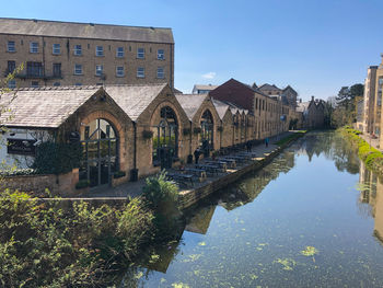 Arch bridge over river amidst buildings against sky