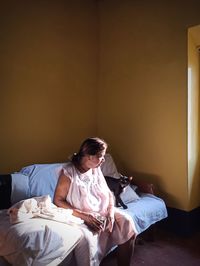 Woman looking away while sitting on bed