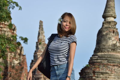 Portrait of smiling young woman standing against temple