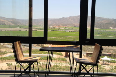 Empty chairs and table on field against clear sky