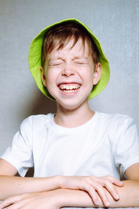 Portrait of a capricious boy in a light green panama hat, on a white background