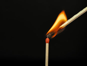 Close-up of burning matchstick against black background