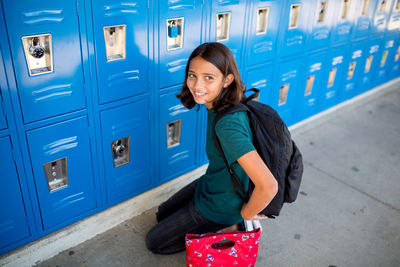 Tween girl smiles in front of her locker at middle school
