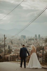 Rear view of people walking on bridge in city