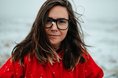 Young happy tourist in eyeglasses with piercing looking at camera between deserted ground in snow