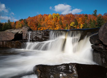 Scenic view of waterfall against sky during autumn