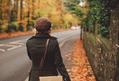 Rear view of woman walking on road in forest