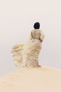 Woman in traditional clothing standing on sand at beach