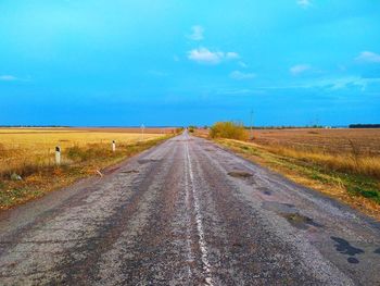 Road amidst field against sky