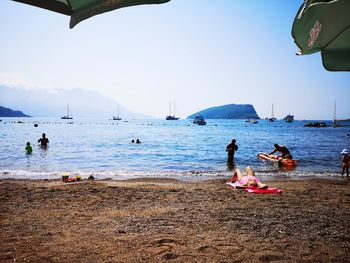 People enjoying at beach against sky